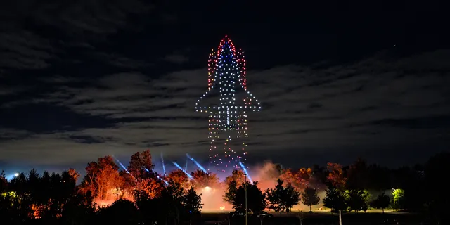 Illuminated drones forming a rocket above the trees at Discovery 2026 in Belgium