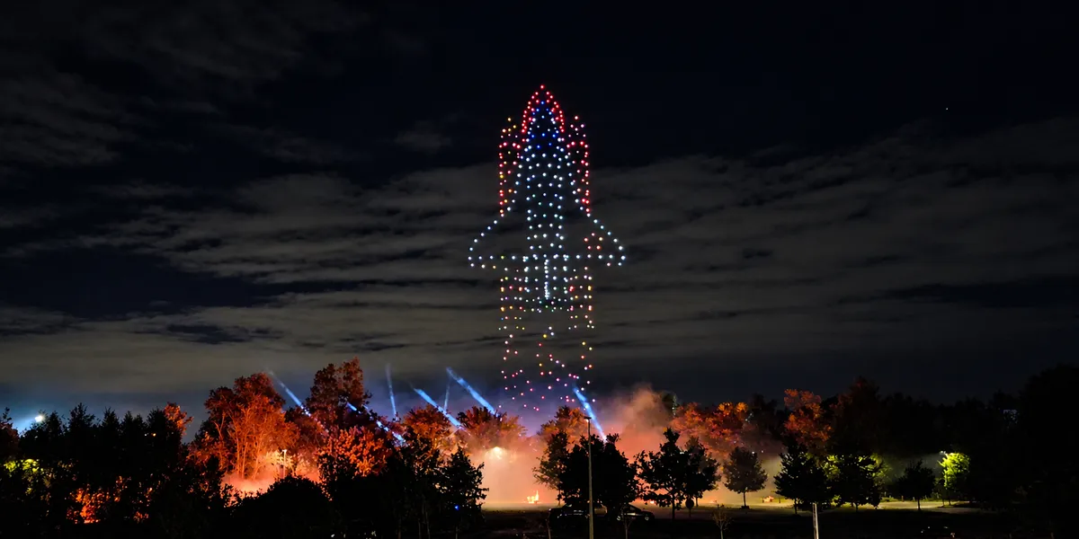 Illuminated drones forming a rocket above the trees at Discovery 2026 in Belgium